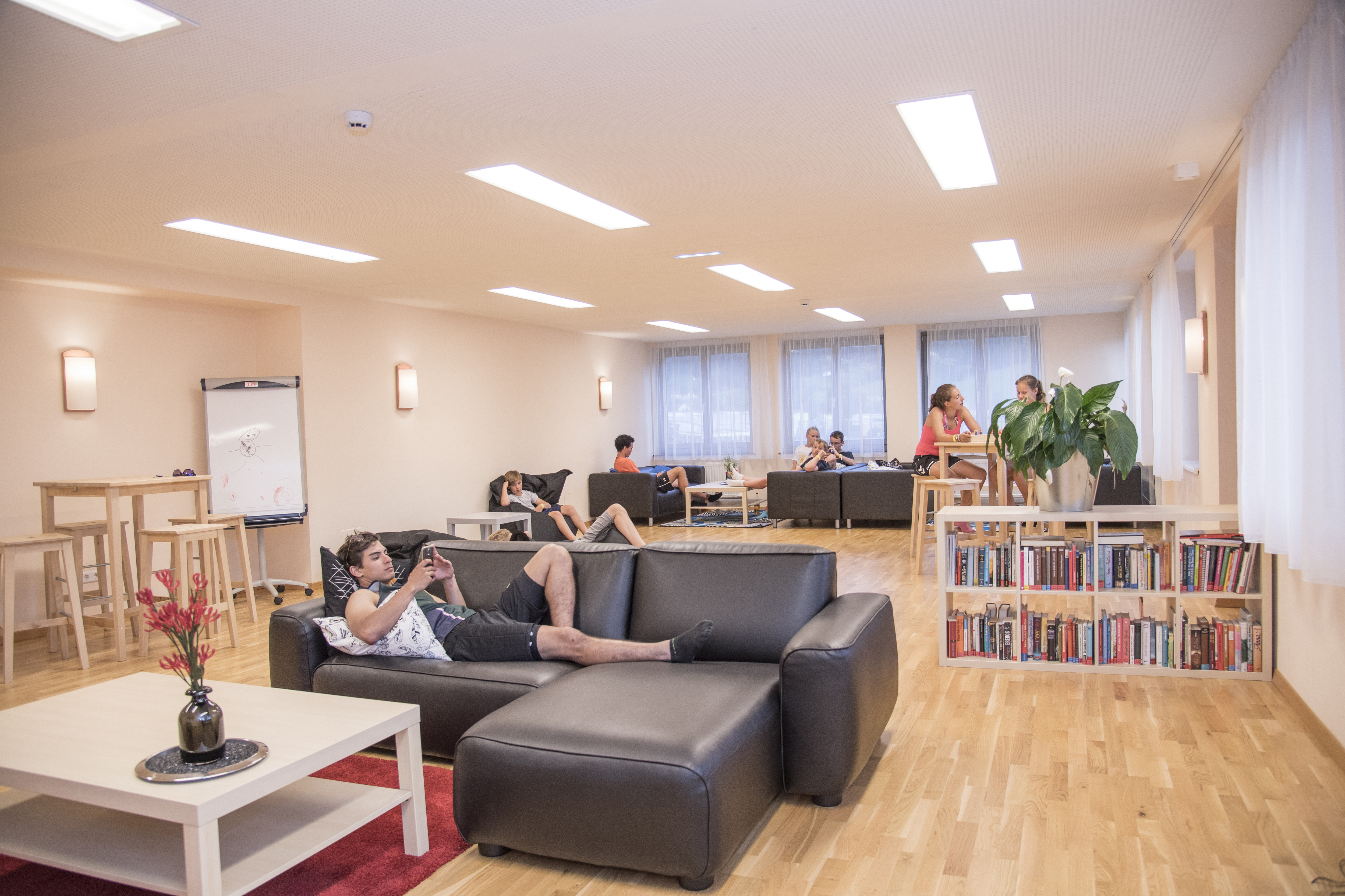 Teens beim Relaxen im gemütlichen Chillraum im JUFA Hotel Lungau. Der Ort für erholsamen Familienurlaub und einen unvergesslichen Winter- und Wanderurlaub.