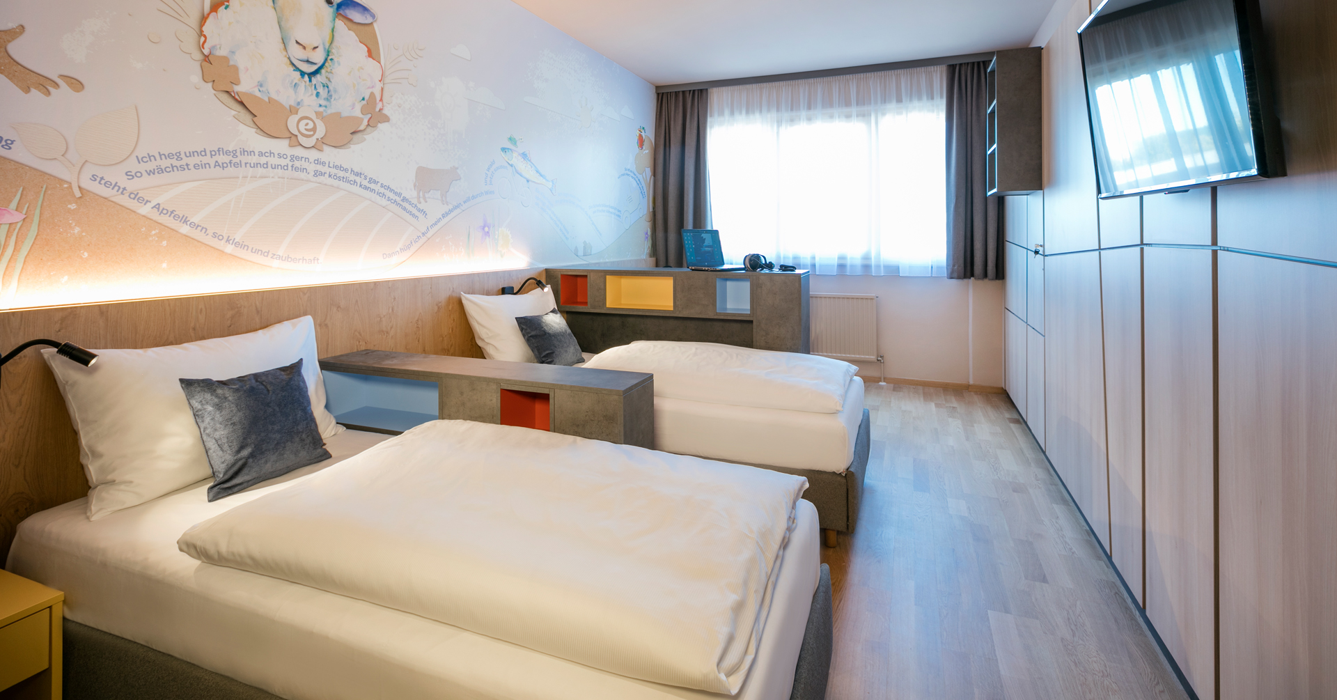 Sie sehen ein Doppelzimmer mit Fernseher im Schülercampus Weiz. Der Ort für erfolgreiche und kreative Seminare in abwechslungsreichen Regionen.